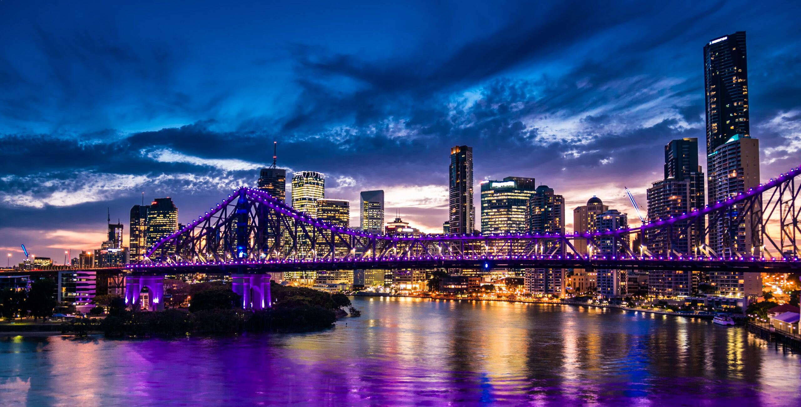 Vibrant night time panorama of Brisbane city with purple lights on Story Bridge, Australia