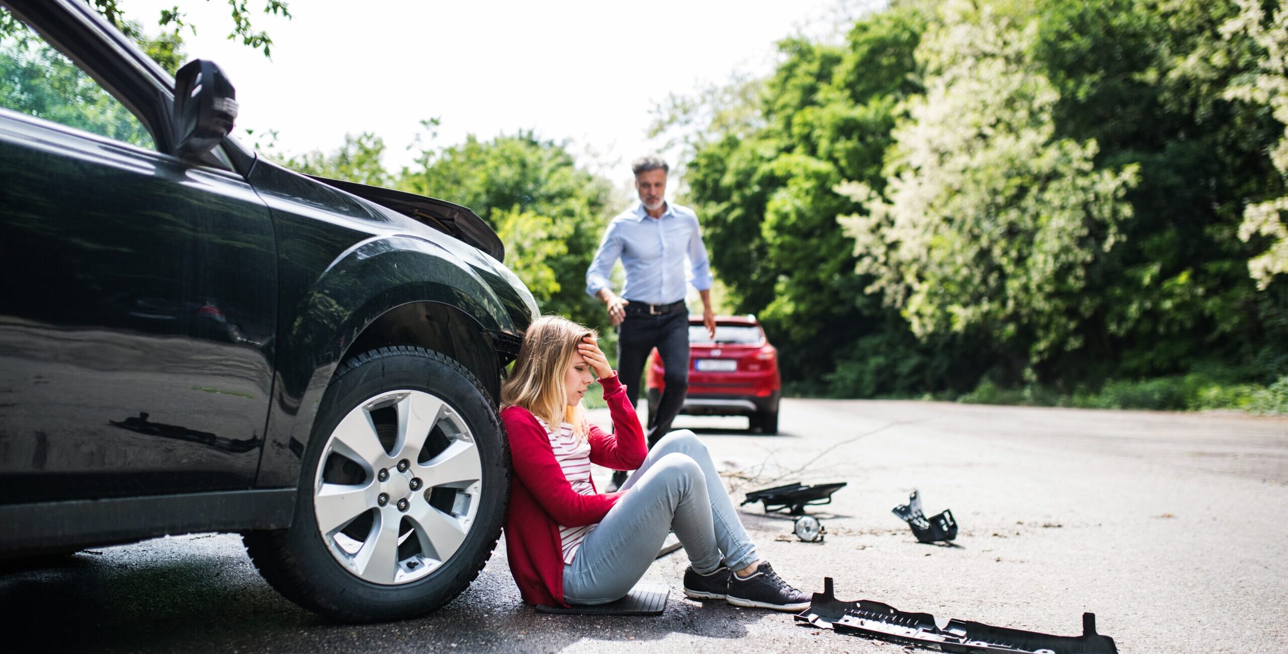 Young frustrated woman by the car after an accident and a mature man running towards her.